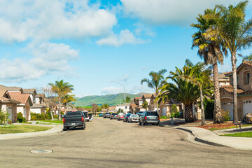Beautiful houses with nicely landscaped front the yard, and cars parked on a sidewalk in small town in California.