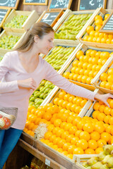 Lady choosing oranges in greengrocers