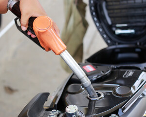Hand fuel the motorcycle at a gas station