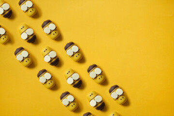 cute Bee cake pops pattern. yellow cartoon bees fly in a row on a yellow paper background