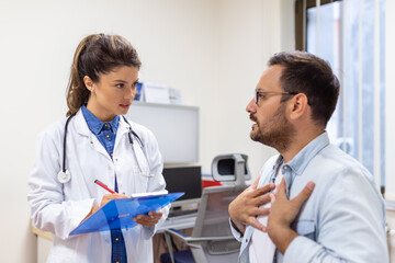Fototapeta premium Experienced doctor discussing with patient his private medical file. Young man checking up with his MD, and consulting about the way of his health treatment and health insurance.