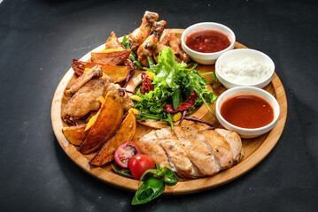 grilled potatoes and meat with various sauces and greens