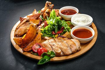 grilled potatoes and meat with various sauces and greens