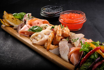 assorted fish and seafood on a wooden tray
