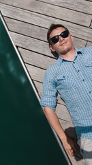 A guy in a blue shirt lies on the pier and smiles