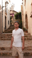 A guy in a white T-shirt on the background of the street in the Spanish style