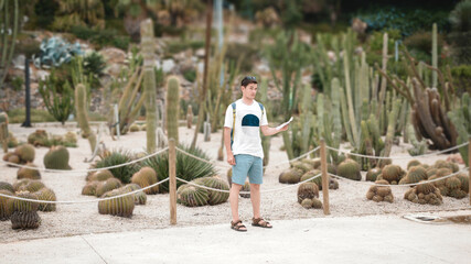 A male tourist is looking for a way on the map. Against the background of cacti