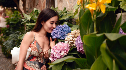 Girl sniffing huge purple and pink flowers