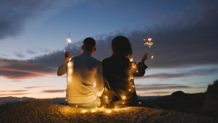 Couple enjoy valentine's day seated with sparkle against the sunset