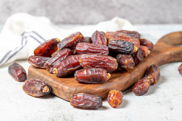 Date fruit on stone background. Organic pile of medjoul dates on a wood serving board. Ramadan food. close up