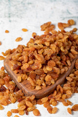 Raisins on stone background. Organic pile of yellow raisins on a wooden serving board. Dried healthy nuts. close up