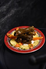 dolma  shaped on a red plate with lemon and carrot