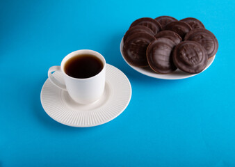 photo of lots of chocolate chip cookies on a plate next to a cup of hot drink