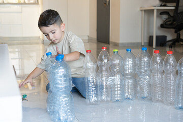 Child build a tower from recycled plastic bottles. Idea uses of old plastic bottles.