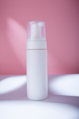 White bottle with dispenser mockup on pink backdrop in harsh light, no brand template. Cleansing moisturizing facial foam container