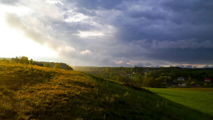Fototapeta na wymiar Stormy couds and sunset sky over fields.