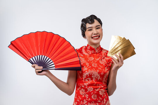 Beautiful Asian woman wearing cheongsam holding red fan and gold envelope isolated on white background, Happy Chinese New Year.