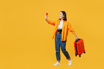 Young woman wear summer clothes do selfie shot on mobile cell phone with bag isolated on plain yellow background. Tourist travel abroad in free spare time rest getaway Air flight trip journey concept