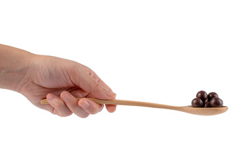 Hand and chocolate balls on wooden spoon on transparent background.