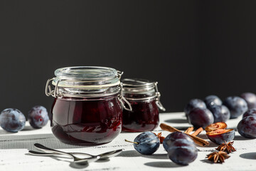 plum and prune jam with spices on a white wooden surface on a dark gray background, the concept of home canning