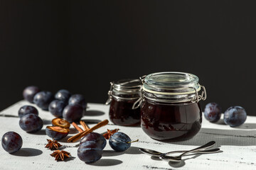 plum and prune jam with spices on a white wooden surface on a dark gray background, the concept of home canning