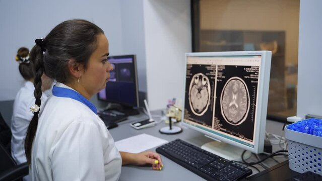 Attentive lab technician checks carefully the brain image on the screen. Magnetic resonance examination in the hospital.