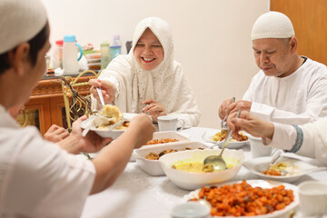 Cheerful muslim woman serving food to her brother at dining room during the Eid Mubarak ramadan celebration.