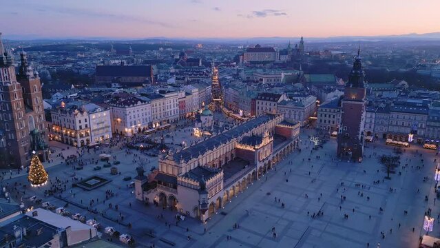 Przelot nad Rynkiem Gł&oacute;wnym w Krakowie po zachodzie słońca. Ratusz, Sukiennice, Kości&oacute;ł Mariacki, Wawel. Polskie zabytki widziane z drona.