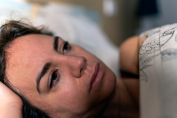 closeup of a pensive young woman with teary eyes lying on a bed. Depression and mental health concept