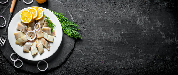 Sliced salted herring with dill, lemon and onion rings.