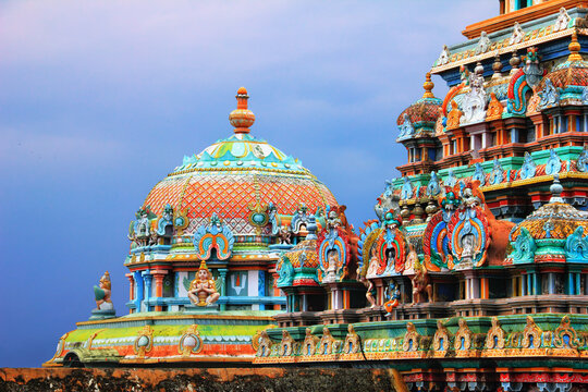 Beautiful view of colorful gopura and cupola in the Hindu Jambukeswarar Temple against the background of cloudy blue sky in Srirangam island, Trichy (Tiruchirappalli, Tiruchi), Tamil Nadu, South India