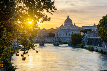 St. Peter's basilica dome and St. Angel bridge over Tiber river at sunset in Rome, Italy