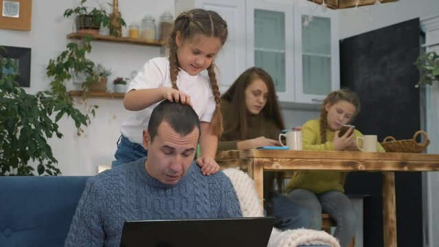 work at home. Family dad working on laptop while sitting on couch at home. small kid plays with busy father. family image of life of isolation.Dad, kid are looking in at laptop.Internet technologies.