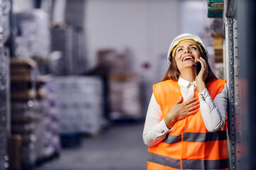 A businesswoman is laughing in storage while having phone conversation on a break.