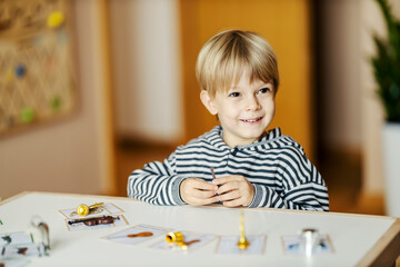 A happy boy is learning music instruments while sitting in kindergarten and playing with educational games.