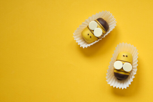 Flat lay bee cake pops on a yellow background. Top view