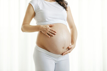 Close up of a pregnant woman caressing her belly.