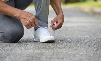 senior man tying shoelace getting ready for exercise, concept of preventing the risk of falls in the elderly - obrazy, fototapety, plakaty