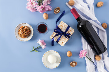 beautiful Passover blue backgroundof Jewish Passover. top view of a bottle of red kosher wine, glasses of wine, matzah, nuts, egg on a plate.