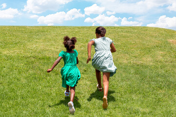 Rear view of two African girls running in a grass field