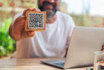 Man inbackgorund showing qr code menu at the cafe. Digital online modern people lifestyle and job. Laptop computer. Cliente use qr code to see the menu and pay the bill at the restaurant.