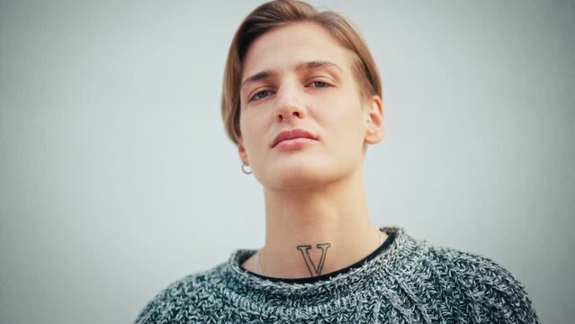 Portrait of a serious and confident caucasian woman. A queer person with short hair looking at the camera.