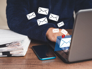 Businesspeople in a sweater using a laptop receives a new message with email icons while sitting at...