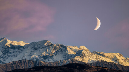 Snowy mount Canin at sunrise. View  from the Udine city castle. Moon over snowy Julian alps. Friuli...