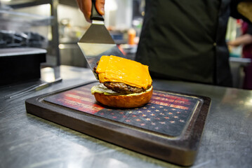 chef hand cooking cheeseburger on restaurant kitchen