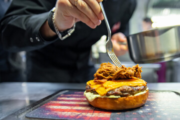 chef hand cooking cheeseburger on restaurant kitchen