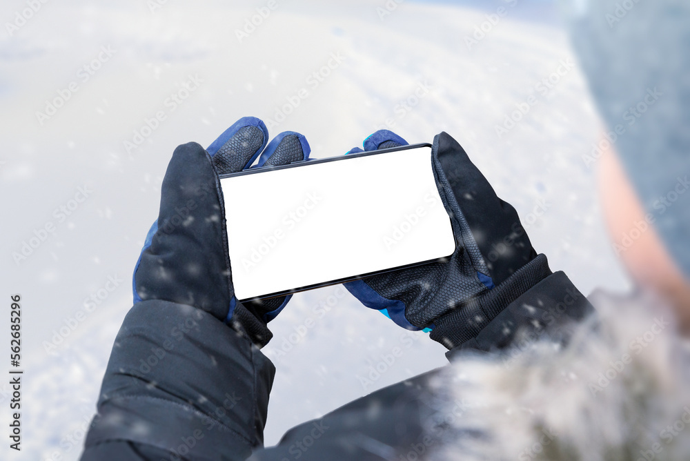 Aufkleber phone in boy hands in horizontal position. boy in a winter jacket, gloves and a cap. isolated displa