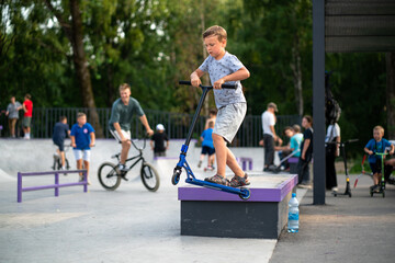 boy exercising on a scooter in a skatepark - obrazy, fototapety, plakaty