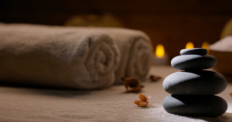 Spa salon equipment. Close up shot of massage hot stones with little flowers around and towels with...
