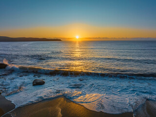 Aerial sunrise seascape with clear skies and sun above the horizon